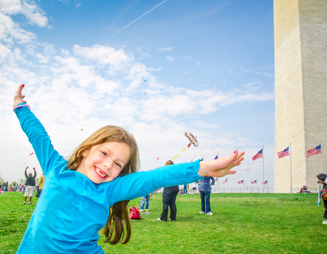 A happy kid posing like she's flying in the air during the Kite Festival at the National Mall in Washington, DC.