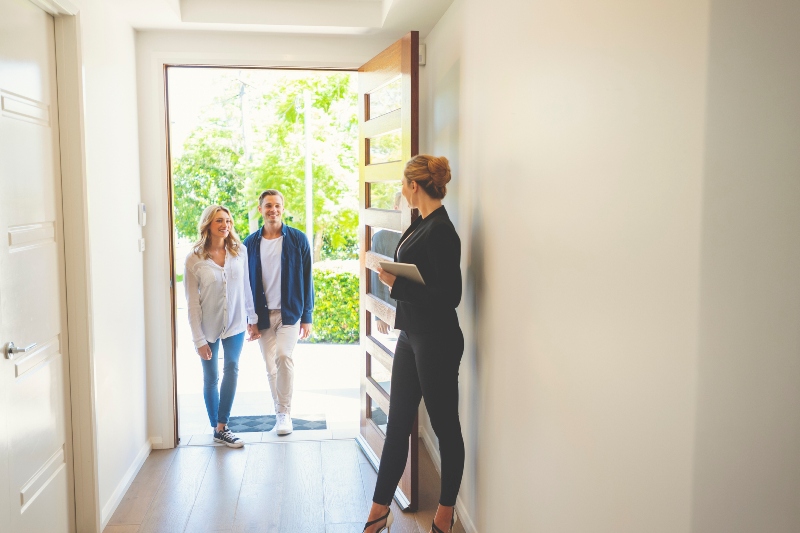 A Real Estate Agent touring a couple inside a luxury home for sale.