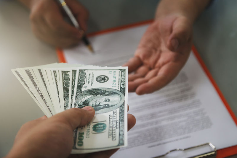 A man signing a contract and receiving a money